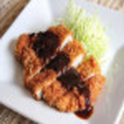 Porções: Tonkatsu - Porção (Ingredientes: Lombo suíno empanado e frito, acompanhado de repolho fatiado e molho picantes. Um dos pratos mais populares da culinária japonesa, preferidos das crianças , além de servir muito bem como aperitivo para acompanhar uma cerveja)