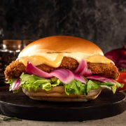 Linha Clássicos: Chiken Classic Jerrajê® - Linha Jerragê (Ingredientes: Bacon, Cebola Roxa, Clássico Frango Empanado Jerrajê® Regado em Molho Especial, Folhas de Alface Americana, Maionese, Pão Com Gergelim, Picles, Queijo Cheddar, Queijo Mussarela, Tomate em Rodelas)