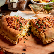 Calzone: Americano - Calzone Grande (Ingredientes: Bacon, Calabresa, Catupiry, Cebola, Champignon, Milho, Mussarela, Orégano, Ovo, Palmito)