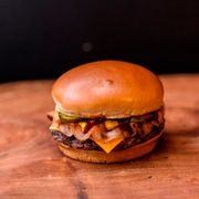 Hambúrguer: Cheeseburguer com Bacon - Cheeseburger (Ingredientes:  Bacon,  Duas fatias de picles,  Duas fatias de queijo,  Hamburguer 100% bovino de 160g grelhado na brasa,  Ketchup,  Mostarda, Pão brioche)