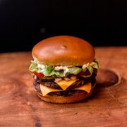 Hambúrguer: Cheeseburguer Salada com Bacon - Cheeseburger (Ingredientes:  Alface,  Bacon,  Cebola,  Duas fatias de picles,  Duas fatias de queijo,  Hamburguer 100% bovino de 160g grelhado na brasa,  Ketchup,  Maionese,  Tomate, Pão brioche)