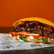 Hambúrguer: Costela no Baguete - Hambúrguer (Ingredientes: Pão baguete, Costela Desfiada, Mussarela, Queijo coalho selado, Rúcula, Tomate, Onion rings, Barbecue, Maionese da casa)