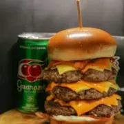 Burguer Artesanal: Jd. Irene - Burguer Artesanal (Ingredientes: Três Burgers Suculentos de 150g cada, Fatias de Queijo Prato e Cheddar Derretido, Crocante de Bacon, Picles, Pão Brioche Dourado, Maionese da Casa)