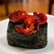 Especialidades: Mini Polvo Idako (unidade) - Uma base delicada de arroz envolta em folha de nori, finalizada com mini polvo levemente apimentado e envolvido em molho oriental brilhante. Uma combinação marcante entre textura, frescor e intensidade.