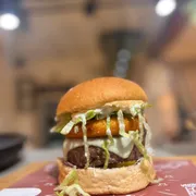 Hambúrguer: BURGUER DO MÊS - Hambúrguer (Ingredientes: Pão fabricação própria, Blend 200g, Medalhão de muçarela empanado, Maionese de alho assado, Cebola roxa, Tomate, Picles de pepino, Alface americana)