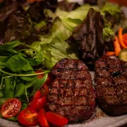 Porções: Mignon Grill & Salada - Mignon suculento feito no broiler ao ponto da casa, com mix de salada fresca. Acompanhado de uma farofa crocante e molho da casa.