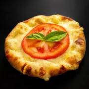 Esfihas salgadas: Esfiha Margherita - Massa de esfiha com fubá, queijo mussarela, tomate fatiado e manjericão fresco.