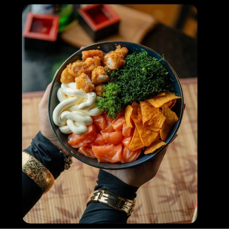 POKE: Poke Tilapia Empanada Com Salmão - 200 g arroz japonês temperado 50 gramas salmão fresco em cubos 50g tilapia empanada 40 g crean chessecouve crispy e doritos