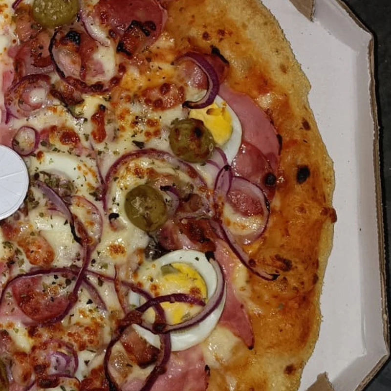 Tradicionais: Da casa - Pizza Grande (Ingredientes: Azeitona, Bacon, Cebola Roxa, Milho, Molho de Tomate Caseiro, Mussarela, Orégano, Presunto)
